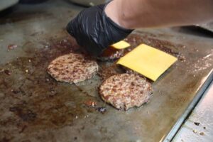 cook making a burger patty with cheese