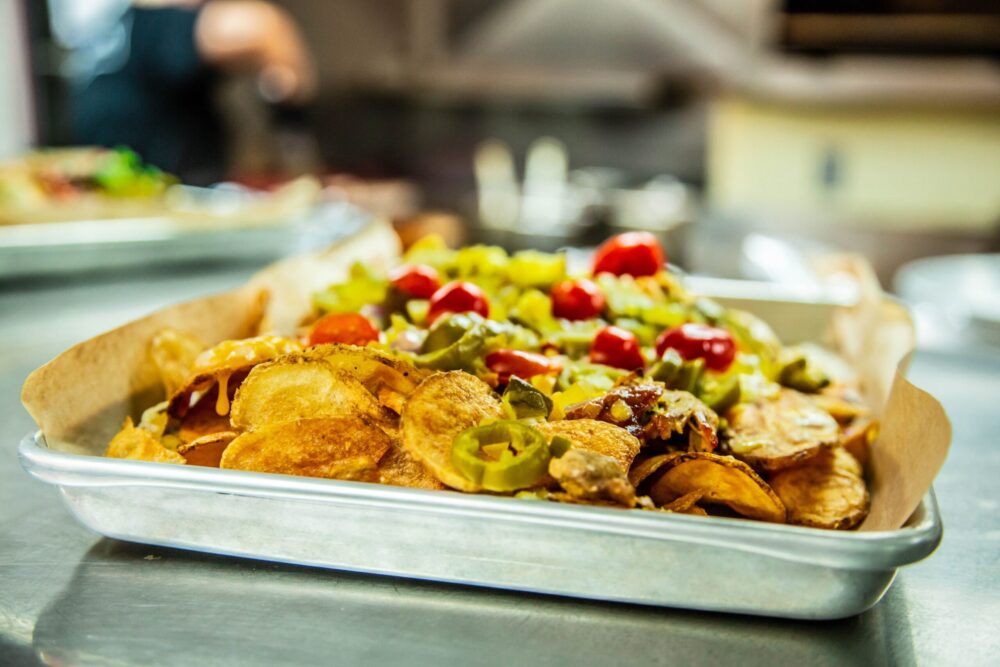 Nachyo Nachos fried house chips covered in jalapenos tomatos and beef brisket on a white plate